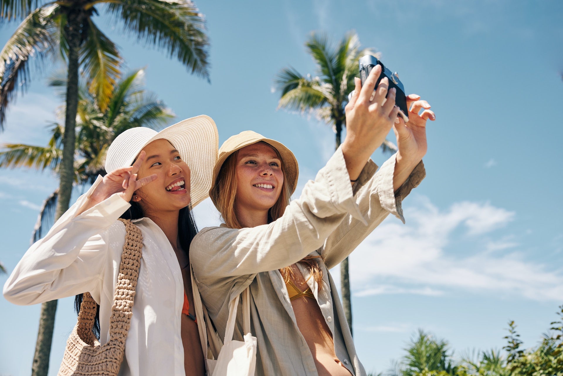 Ladies taking a selfie wearing wool hats with a tropical background