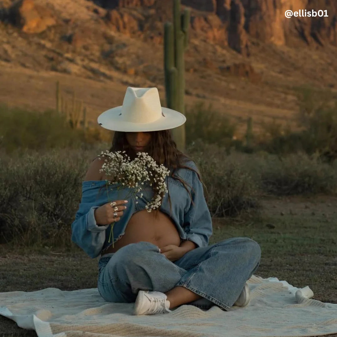 Person sitting on a blanket in a desert landscape holding flowers