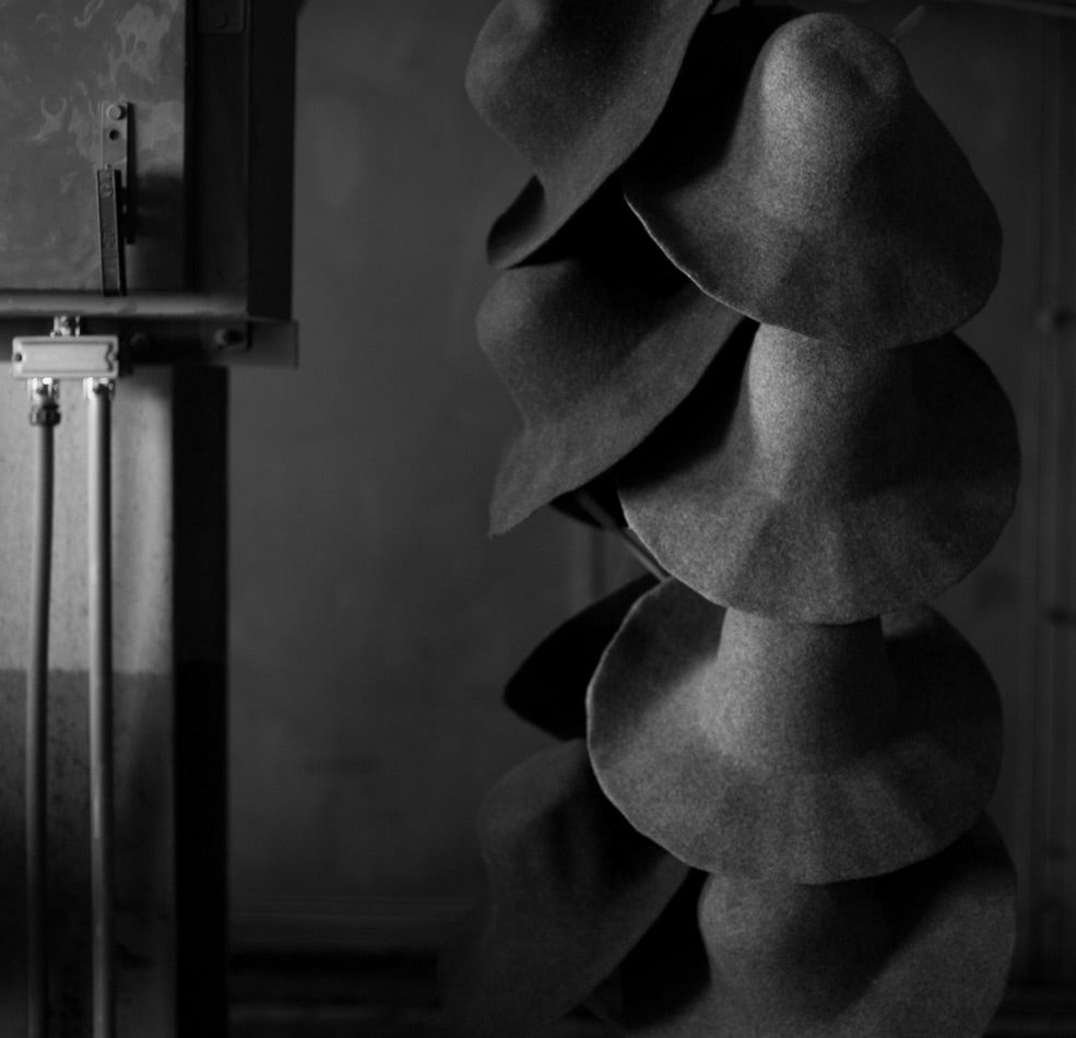 Dark straw hat blanks on a hat stand 