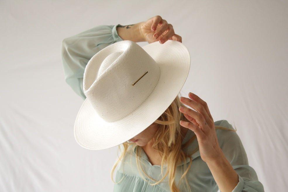 Modern white straw hat with a medium-length brim and metal accent piece 